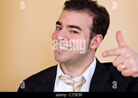 Goofy lächelnd Geschäftsmann zeigen und versuchen zu handeln, wie er ein cooler Typ ist. Geringe Schärfentiefe mit Fokus auf das Gesicht. Stockfoto