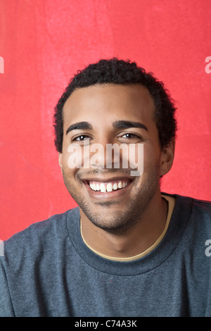 Ein afroamerikanischer Mann lächelt, schaut in die Kamera. Er sieht wie jemand mit Initiative, Ehrgeiz, und hart arbeiten können. Stockfoto