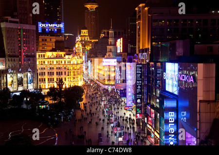 Fußgänger in der Nacht zu Fuß vorbei an Geschäften auf Nanjing Road, Shanghai, China Stockfoto