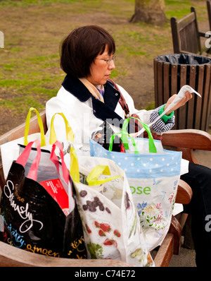 Lady prüft shopping Rechnung im Park, London, England, UK, Europa Stockfoto