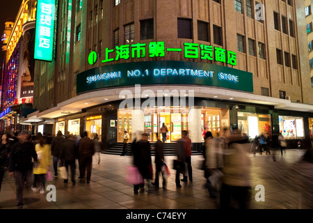 Fußgänger in der Nacht zu Fuß vorbei an Geschäften auf Nanjing Road, Shanghai, China Stockfoto