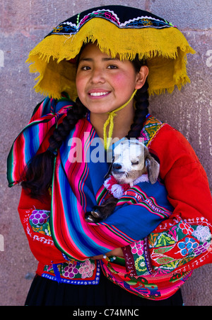 Peruanische Mädchen in bunten Trachten, die mit einem Lamm auf hier Arm Stockfoto
