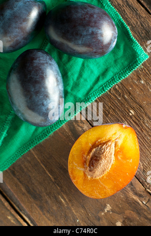 Halbierte Pflaumen mit grünen Serviette auf Holz Stockfoto