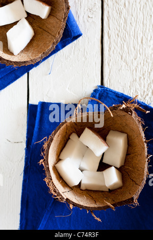 Kokos-Stücke in einer Shell mit blauen Serviette auf weißem Holz Stockfoto
