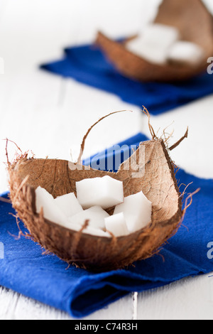 Kokos-Stücke in einer Shell mit blauen Serviette auf weißem Holz Stockfoto