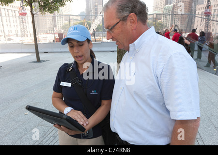 Ein Leitfaden bei der National 9/11 Memorial in New York City. nutzt eine iPad um Richtungen zu einem Besucher. Stockfoto