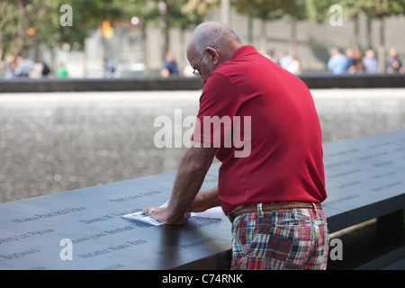 Ein Besucher schafft ein Einreiben mit einer der Namen an das National September 11 Memorial in New York City. Stockfoto