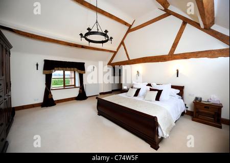 Master-Schlafzimmer mit einer gewölbten Decke in einer umgebauten Scheune in der Nähe von Malvern, Worcestershire UK Stockfoto