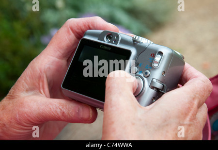 Nahaufnahme einer Person Drücken einer Taste auf der Rückseite von einem Punkt und schießen Kompaktkamera. Stockfoto