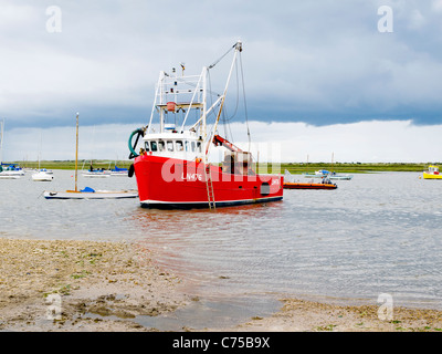 Roten Fischerboot im Hafen von Norfolk Brancaster Staithe an einem regnerischen Tag Stockfoto