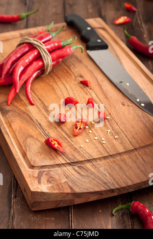 In Scheiben geschnittene rote Chilischoten auf Holzbrett Stockfoto