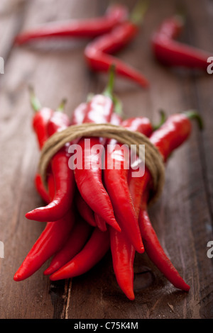 Rote Chilischoten mit einem Seil auf Holz gefesselt Stockfoto