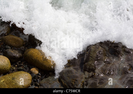 Steinen am Rand Wassers werden von einer Flut gewaschen. Stockfoto