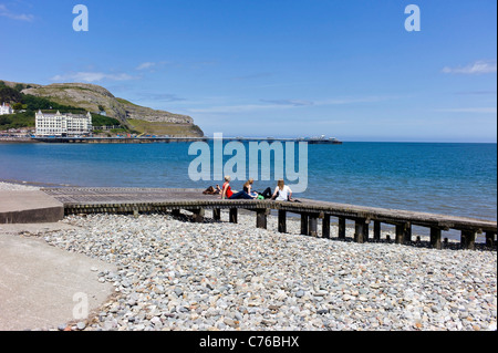 Junge Studentinnen Sonnenbaden auf einem hölzernen Steg an Llandudno Küste, Meer, Pier, great Orme mit blauem Himmel. Stockfoto