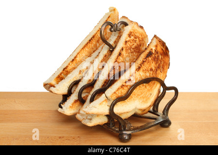 Toast in einem Rack auf eine hölzerne Arbeitsplatte vor einem weißen Hintergrund Stockfoto