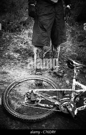 Schlamm bedeckt Mountainbike und Fahrer schwarz / weiß Stockfoto