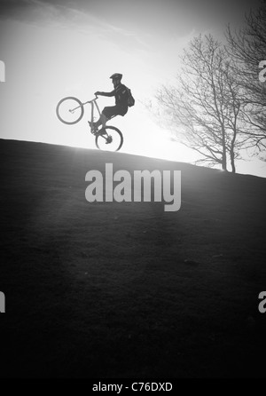 Mountainbiker, die englischsprachige eines Wheelie / manual in sunset schwarz / weiß Stockfoto