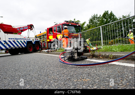 Erholung Arbeiter vorbereiten, die Szene von einem schweren Verkehrsunfall mit einem Feuerwehrfahrzeug und ein Auto zu löschen. Stockfoto