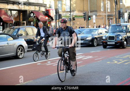 Radfahrer im Rush Hour-Verkehr in der Nähe des Buckingham Palace London, Großbritannien Stockfoto