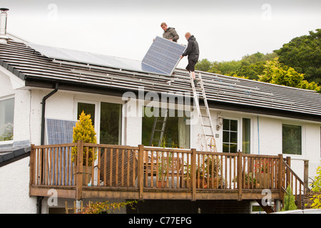 Techniker Montage solar Photovoltaik Paneele zu einem Haus Dach in Ambleside, Cumbria, UK. Stockfoto