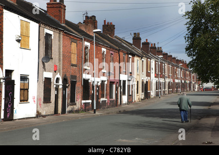 Middleport Bereich des Stoke-on-Trent die geräumt und mit Brettern vernagelt ein Elderley Mann geht vorbei an verschalten Häuser in Travers Straße. Stockfoto