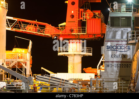 Laden eine Aufbocken Lastkahn mit Wind Turbine Teile in der Nacht in Mostyn, für den Offshore-Windpark Walney. Stockfoto