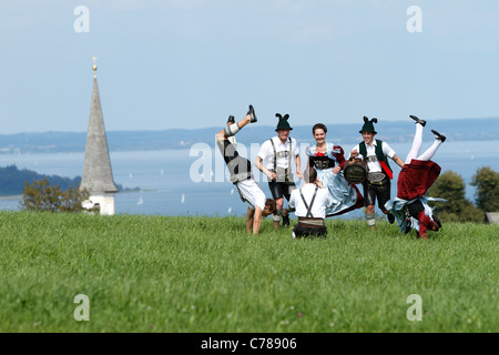 Junge Bayern fotografiert beim laufen und Saltos auf einem Feld Gras in bayerischer Tracht, Hittenk Stockfoto