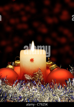 Weihnachtskerze und rote Kugeln. Eine festliche Komposition Stockfoto