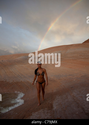 USA, Utah, Lake Powell, junge Frau trägt Bikini und walking, Regenbogen im Hintergrund Stockfoto