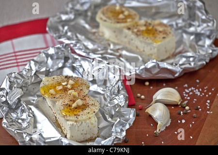 Feta-Käse mit Zwiebeln und Knoblauch in Alufolie gebacken Stockfoto
