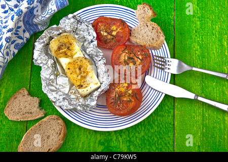gebackene Feta-Käse in Alufolie im Ofen geschmort mit Tomaten, serviert mit Brot Stockfoto