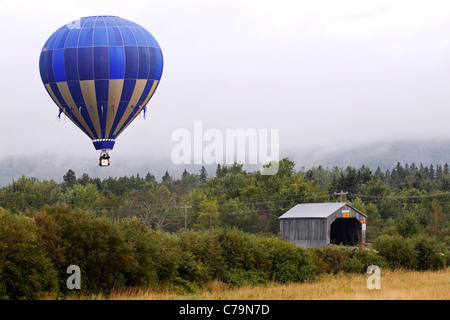 Ein Heißluftballon fliegt über Plumweseep Covered Bridge an der Atlantic International Balloon Fiesta 9. September 2011 in Sussex. Stockfoto