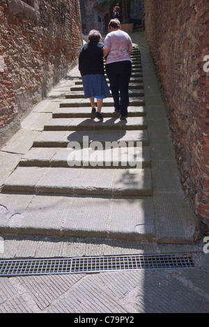 Zu Fuß entfernt, ist eine ältere Frau Stadt Treppe hinauf durch ihre weibliche Helfer in Citta della Pieve, Italien geholfen. Stockfoto