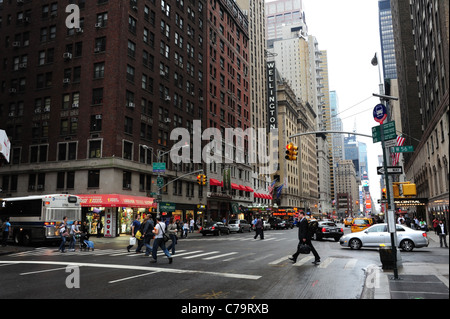 Westen am Nachmittag Straßenansicht Fußgänger überqueren 7th Avenue an der Kreuzung West 56th Street, Blick in Richtung Times Square in New York Stockfoto