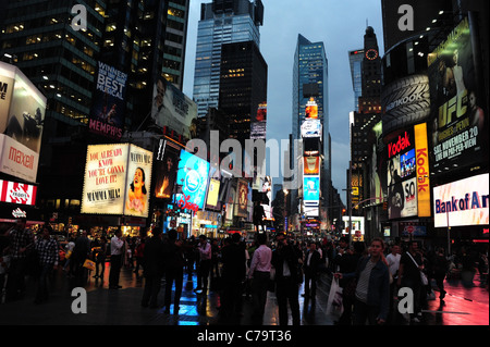 Abenddämmerung Menschen, nassem Boden Reflexionen, Leuchtreklamen, Wolkenkratzer, Times Square, Blickrichtung Times Tower in New York City Stockfoto