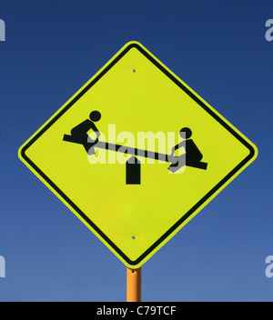 Spielplatz-Straßenschild mit Stuhl sah in gelb und schwarz auf blauen Himmelshintergrund Stockfoto