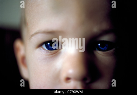 Ein sehr kleiner Junge mit großen blauen Augen starrt auf die Kamera für dieses extreme close-up Portrait, das seine Konzentration zeigt. Stockfoto