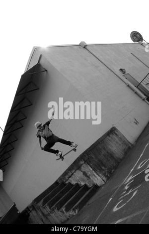 Ein Junge Skateboarder startet aus einer konkreten Laderampe in einem städtischen Umfeld. Stockfoto
