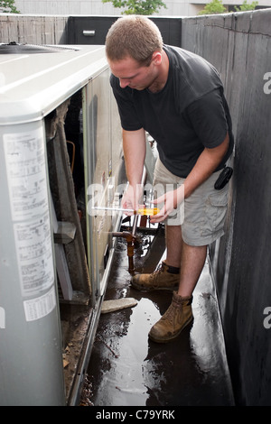 Eine junge HLK-Techniker arbeiten an einem kommerziellen Luft-Anlage auf dem Dach. Stockfoto