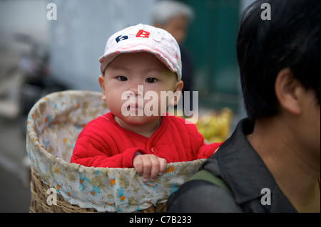 Chinesische Migranten Frau mit einem Baby auf dem Rücken mit einem Bambuskorb in Peking, China.16 Sep 2011 Stockfoto