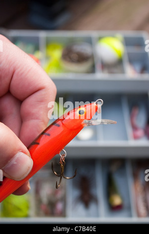 Ein Fischer wählt den Verlockungen aus seiner Tackle Box, die er vor sich geht, mit Angeln zu gehen. Stockfoto