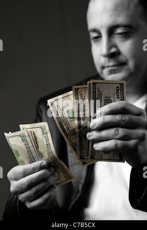 Einem krummen aussehender Mann eine Handvoll von hundert-Dollar-Scheine zu zählen. Geringe Schärfentiefe. Stockfoto