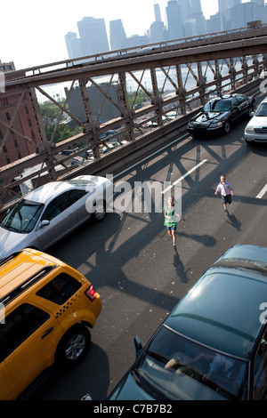 Zwei junge Kinder laufen wild auf der Brooklyn Bridge zwischen Verkehr. Stockfoto