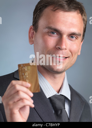 Lächelnd Geschäftsmann mit einer gold Kreditkarte in den Händen Stockfoto