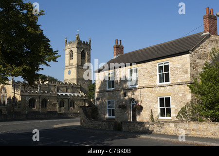 400 Jahre alte Kalkstein Bauernhaus mit St.-Peter Kirche im Hintergrund, Barnburgh, Yorkshire, England. Stockfoto