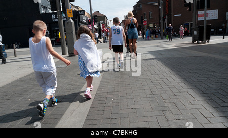 Rückansicht des Mutter und Kinder in den Sommerferien einkaufen zu Fuß entlang der Hauptstraße Walthamstow England UK Stockfoto