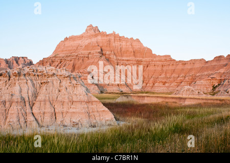 Abendlicht leuchtet auf geformten Türme, die über die Prärie Grasland in Badlands Nationalpark steigen. Stockfoto