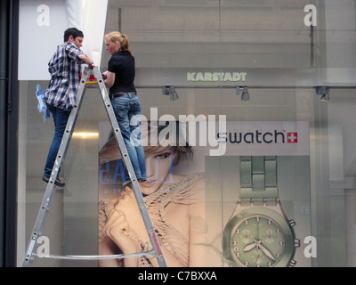 Frauen, die ein Zeichen in einen Swatch Store in Leipzig Sachsen Ostdeutschland anbringen Stockfoto