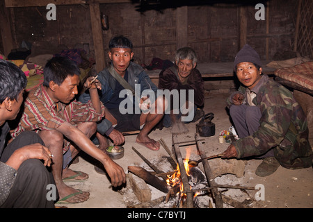 Indien, Nagaland, Longwa, Konyak Naga Stammesangehörigen Runde Feuer zu sitzen, wie Man Opium auf Löffel schmilzt Stockfoto