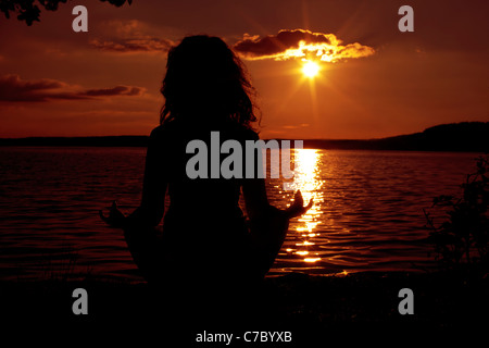 junge Frau tut Yoga bei Sonnenuntergang Stockfoto